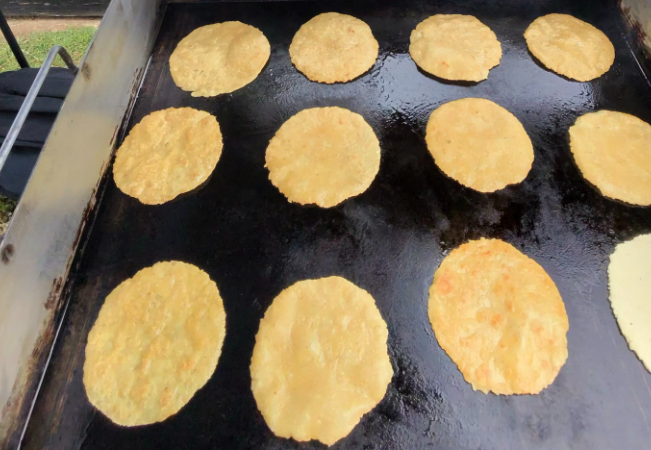Handmade corn tortillas cooking on the flat top