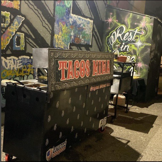 The original Tacos Mina cart parked against a graffiti wall at night
